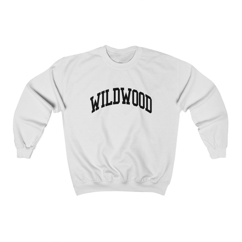 May include: White sweatshirt with the word "WILDWOOD" arched across the chest in black, bold, block letters. The long-sleeved crewneck top is made of a soft material. The sweatshirt is a casual style.