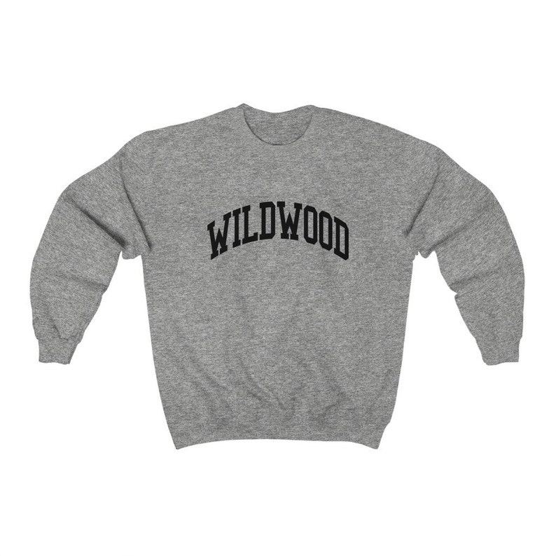 May include: A heather gray sweatshirt with the word "WILDWOOD" arched across the chest in black block letters. The sweatshirt has long sleeves and a crew neck. The fabric appears to be a soft, comfortable material.