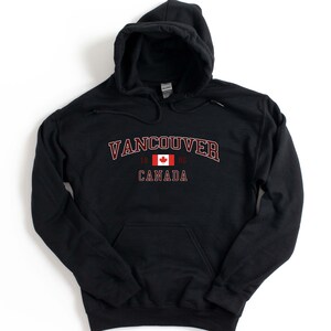 May include: Black hooded sweatshirt with a red and white Canadian flag and the text "Vancouver 1986 Canada" printed on the front.