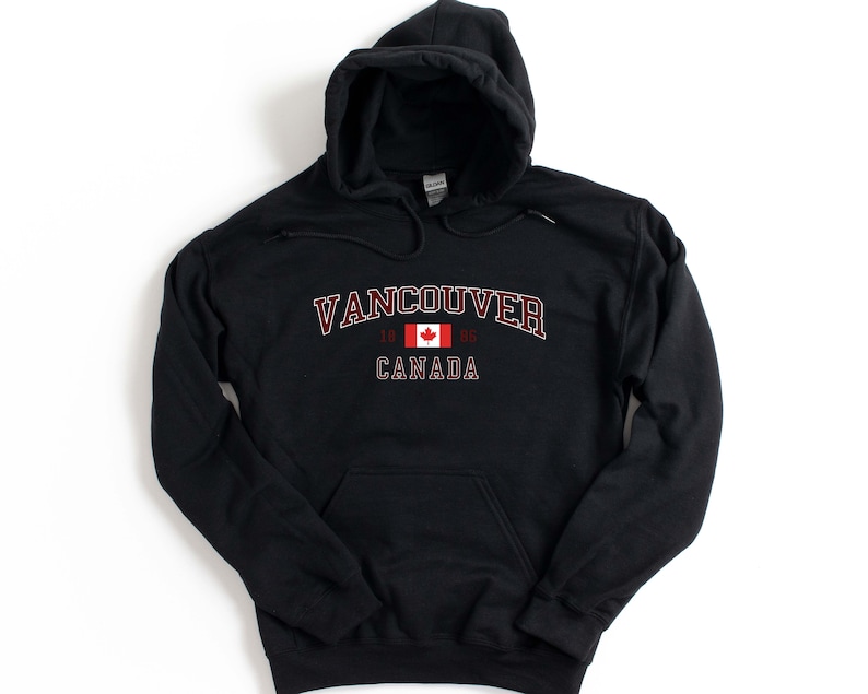 May include: Black hooded sweatshirt with a red and white Canadian flag and the text "Vancouver 1986 Canada" printed on the front.