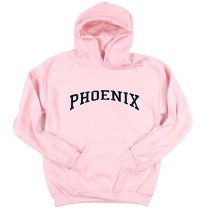 May include: A pink hooded sweatshirt with the word "PHOENIX" printed in a navy blue arched font.