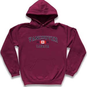 May include: A maroon hooded sweatshirt with a navy blue graphic that says "Vancouver" with the Canadian flag and "1866 Canada" underneath.