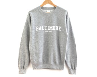 May include: A gray sweatshirt with the text "BALTIMORE MARYLAND" printed in white on the front.