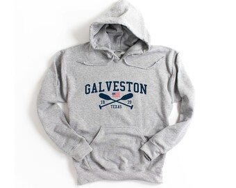May include: Gray hooded sweatshirt with a navy blue print that says "GALVESTON" with an American flag and crossed oars underneath. The text "18 TEXAS 39" is printed below the flag.