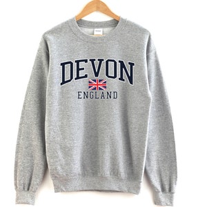 May include: A gray sweatshirt with a navy blue print that says "DEVON ENGLAND" with a small Union Jack flag.