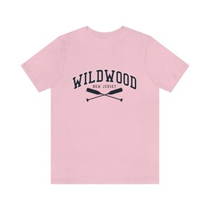 May include: A pink t-shirt with a navy blue graphic of the text "WILDWOOD NEW JERSEY" with two crossed oars.