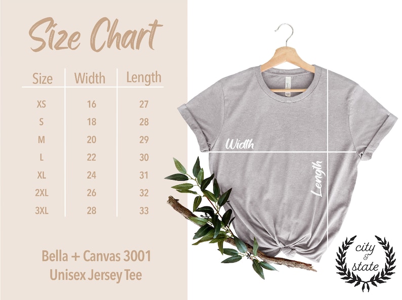 May include: Size chart for a unisex jersey tee shirt, showing measurements in inches for width and length. The chart includes sizes XS to 3XL. The shirt is a light gray color and is hanging on a wooden hanger.