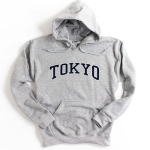 May include: A gray hooded sweatshirt with the word "TOKYO" printed in navy blue on the front.