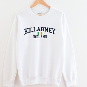 May include: White sweatshirt with a navy blue print that says "KILLARNEY IRELAND" with an Irish flag graphic.