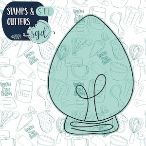 Puede incluir: Un cortador de galletas de árbol de Navidad azul verdoso con contorno negro. El cortador tiene la forma de un árbol de Navidad tradicional con una estrella en la parte superior. El fondo es un patrón blanco de utensilios de cocina y el texto "Sugared Grace Designs".