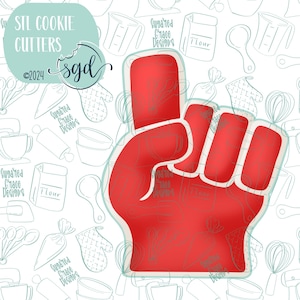 May include: Red cookie cutter shaped like a fist with the index finger pointing up. STL Cookie Cutters is written in the top left corner of the image.  Sgd is written in the top right corner of the image.
