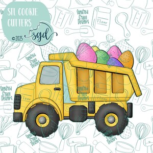 以下が含まれることがあります： カラフルなイースターエッグでいっぱいの荷台を持つ黄色いダンプトラックのクッキーカッター。トラックは黒いアウトラインと黒い車輪を持っています。背景は白いキッチンツールの模様です。