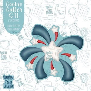 May include: A blue and red cookie cutter in the shape of a starburst. The cutter is on a white background with a pattern of kitchen tools and the text "Suggared Grace Designs".
