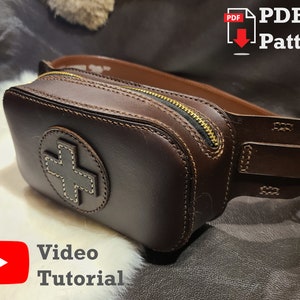 Puede incluir: Una riñonera de cuero marrón con cierre de cremallera y un diseño en forma de cruz. La riñonera tiene un lazo para el cinturón y una hebilla de metal. El texto "PDF Pattern" y "Video Tutorial" es visible en la imagen.