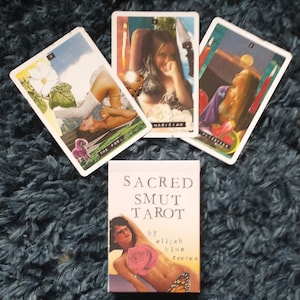 May include: A box of tarot cards with the title "Sacred Smut Tarot" by Elijah Blue Reeves. The box features a collage of a woman with a butterfly and a rose.