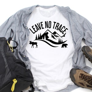May include: White t-shirt with black text that says "Leave No Trace" with a mountain, trees, a moose, and a bear graphic.