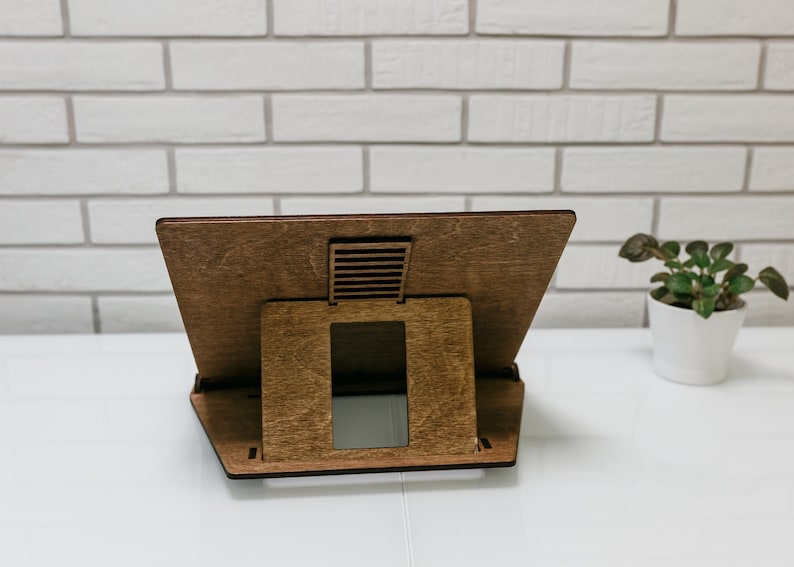 May include: A wooden laptop stand with a brown finish. The stand has a cutout for ventilation and a raised platform to elevate the laptop.