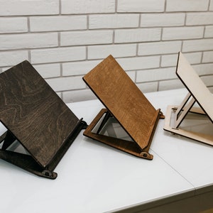 May include: Three wooden bookends in different shades of brown. The bookends are angled and have a simple design.