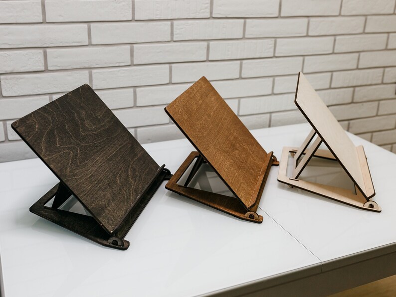 May include: Three wooden bookends in different shades of brown. The bookends are angled and have a simple design.