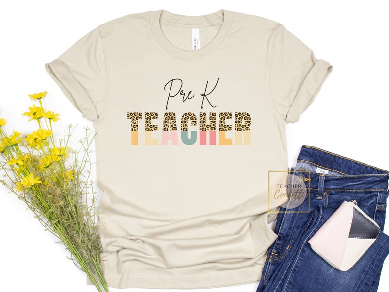 Puede incluir: Una camiseta beige con el texto "Pre K Teacher" en letra negra. La palabra "Teacher" est&aacute; en estampado de leopardo con rayas de colores detr&aacute;s.