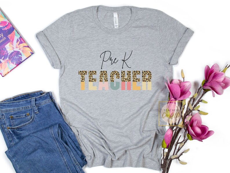 Puede incluir: Una camiseta gris con el texto "Pre K Teacher" en letra negra. La palabra "Teacher" est&aacute; formada por letras de estampado de leopardo con un fondo colorido.