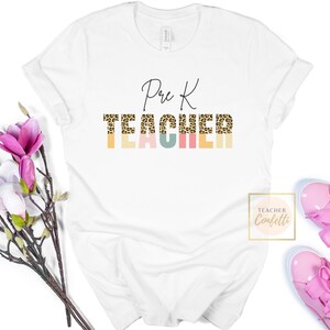 Puede incluir: Camiseta blanca con el texto "Pre K TEACHER" en letra negra. La palabra "TEACHER" est&aacute; en estampado de leopardo con un fondo colorido.