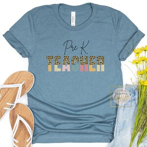 Puede incluir: Una camiseta azul turquesa con el texto "Pre K Teacher" en letra negra. La palabra "Teacher" est&aacute; en letras may&uacute;sculas de colores con un estampado de leopardo.