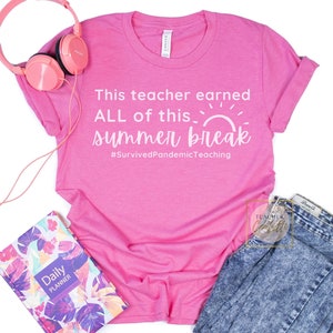 May include: Pink t-shirt with white text that reads "This teacher earned ALL of this... summer break #SurvivedPandemicTeaching". The shirt is laying on a white surface with a pink headband, a planner, and a pair of blue jeans.