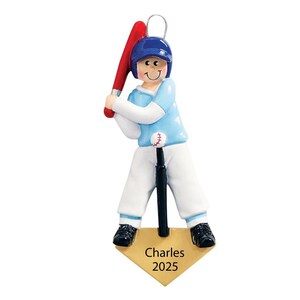 May include: A baseball-themed ornament featuring a batter in a blue helmet and uniform, holding a red bat. The ornament includes a baseball on a tee and a home plate with the name "Charles" and the year "2025".