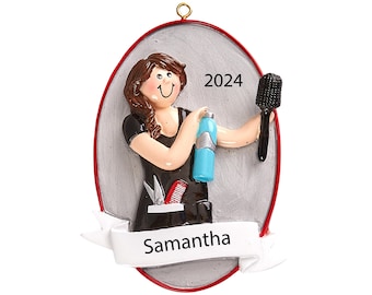 May include: A personalized Christmas ornament featuring a cartoon woman with brown hair, wearing a black smock and holding a hairspray bottle and a brush. The ornament is oval shaped with a silver background and a red border. The text "Samantha" is on a white banner at the bottom and "2024" is at the top.