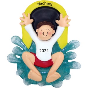 May include: A personalized Christmas ornament featuring a cartoon boy in a white shirt and red shorts, jumping into a pool of water. The ornament is yellow and green with the name "Michael" and the year "2024" printed on it.