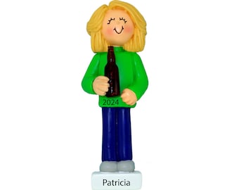 May include: Personalised Christmas bauble depicting a woman with blonde hair wearing a green jumper and blue jeans, holding a brown bottle. The bauble has the year 2024 and the name "Patricia" on the base.