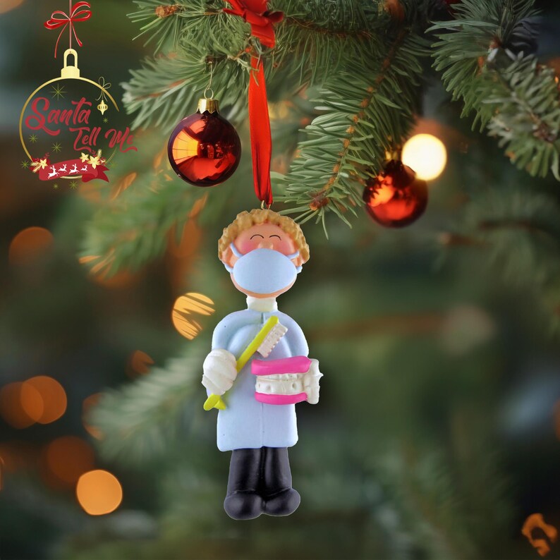 May include: A blue and white Christmas ornament depicting a dentist wearing a face mask and holding a toothbrush and a set of teeth.