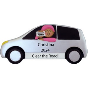 May include: White car ornament with a cartoon driver holding a "Learner's Permit" sign. The car has the name "Christina" and the year "2024" written on it. The text "Clear the Road!" is written below the year.