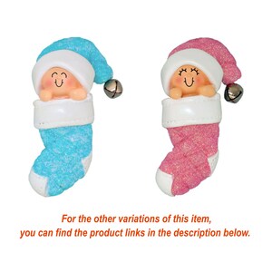 May include: Two Christmas stocking ornaments shaped like baby booties. One is blue with white trim and the other is pink with white trim. Both have a bell on the top.