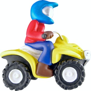 May include: A yellow toy ATV with a blue and red figurine wearing a blue helmet. The figurine is sitting on the ATV and holding the handlebars.