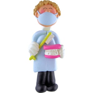 May include: A blue and white figurine of a dentist wearing a blue face mask and holding a toothbrush and a pink set of dentures.