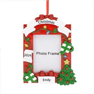 May include: Red and white Christmas photo frame ornament with a white banner that says "Christmas". The frame has a small green tree, a gift, and a stocking on it. The frame says "Photo Frame" and "Emily" at the bottom. The year "2024" is on the stocking.