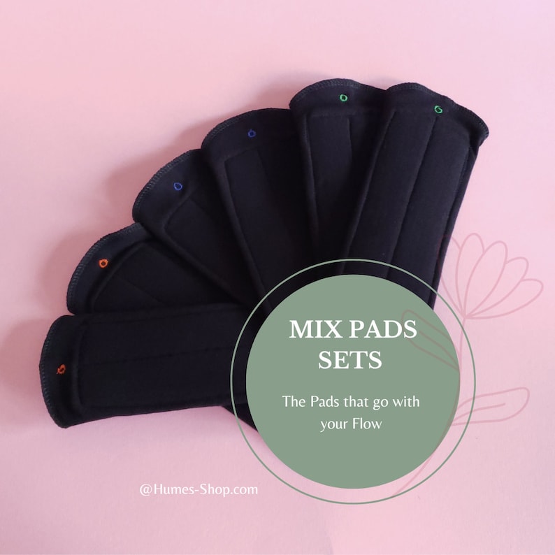 May include: A set of black reusable pads arranged in a fan shape, each with colorful stitching. The pads are displayed on a pink background, with text that reads "MIX PADS SETS" and "The Pads that go with your Flow".