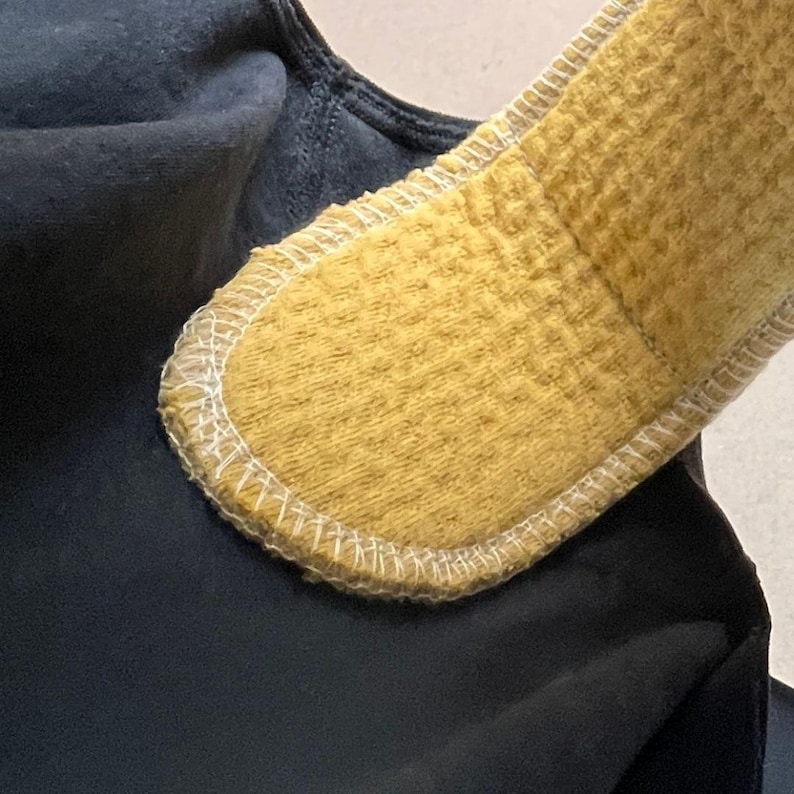 Close-up of the soft Golden Sand organic cotton absorbent surface of a reusable cloth pad positioned inside black underwear, showing the fabric texture and white edge stitching.
