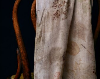 Può includere: Una sciarpa di seta color marrone chiaro con motivi botanici marroni e ruggine, drappeggiata su una sedia di legno.