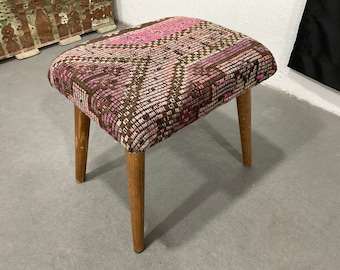 May include: A small, square ottoman with a pink and brown patterned fabric top and four wooden legs.