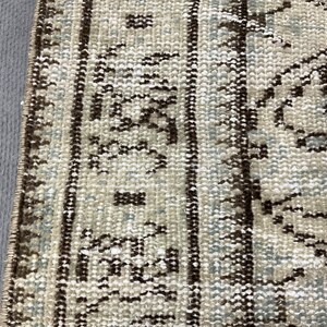 May include: Close-up of a beige and brown patterned rug with a fringe border. The rug has a traditional design with intricate details.
