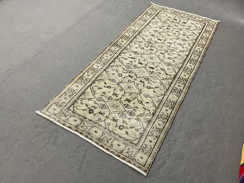 May include: A beige and brown patterned rug with a geometric design. The rug has a fringed edge and is made of a soft, woven material.