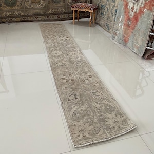 Puede incluir: Un tapete corredor beige con un patrón floral. El tapete tiene un aspecto descolorido y está hecho de un material suave y tejido.
