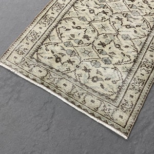 May include: A beige and brown patterned rug with a geometric design. The rug has a fringed edge.