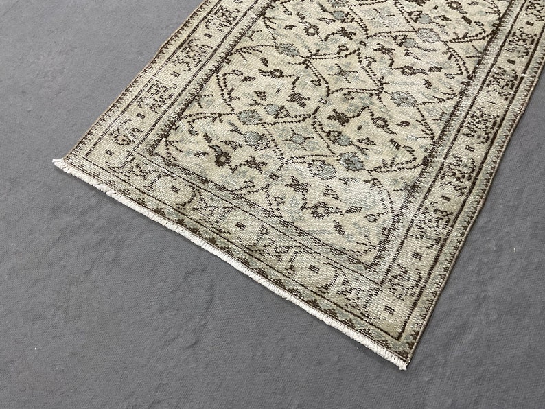 May include: A beige and brown patterned rug with a geometric design. The rug has a fringed edge.