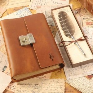 Può includere: Un diario in pelle marrone con un lucchetto e una chiave, e le iniziali "E|Y" incise sulla copertina. Il diario è appoggiato su un tavolo con una scatola che contiene una penna stilografica.