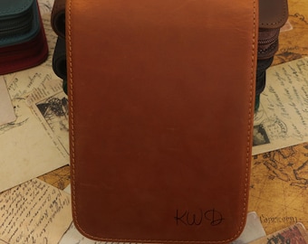 May include: A brown leather pencil case with a zipper closure and the initials "KWD" embossed on the front.