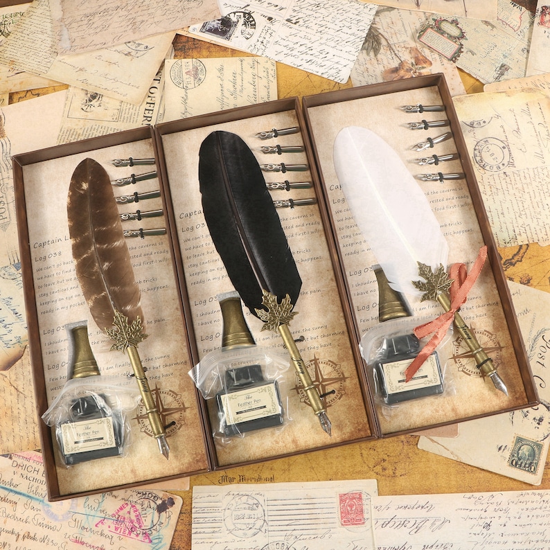 Puede incluir: Tres juegos de plumas de caligraf&iacute;a en cajas de madera. Cada juego incluye una pluma de pluma negra, marr&oacute;n o blanca, un frasco de tinta de vidrio y un juego de plumillas. Las cajas tienen un aspecto vintage e incluyen el texto "Captain Legoss" y "Log 03".